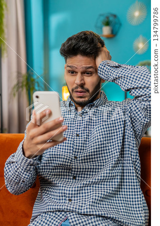Sad Indian man use smartphone surprised by bad news, fortune loss, fail, lottery results, deadline 134799786