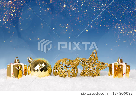 Christmas tree baubles on blue background with white snow and golden lights. Festive winter holiday background. Design with copy space for greeting card, text, advertising, banner, invitation 134800082