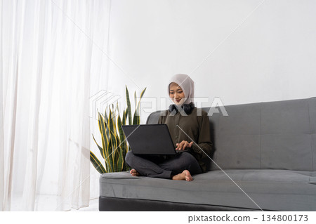 woman with headscarf on video call with headphones and laptop woman with headscarf on video call with headphones and laptop 134800173