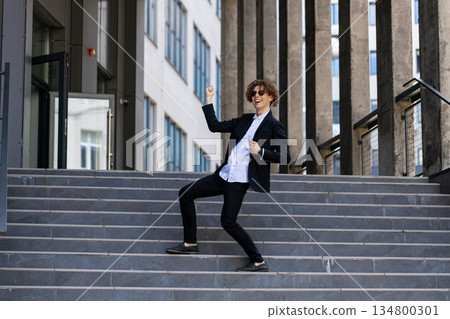 Excited businessman in celebration at steps walking after job interview, promotion, dancing, success 134800301