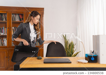 Confident professional woman gathers items before leaving office Confident professional woman gathers items before leaving office 134800538