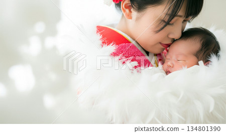 A young mother in a furisode kimono at her coming-of-age ceremony, holding her newborn baby and smiling happily, with copy space A young mother in a furisode kimono at her coming-of-age ceremony, holding her newborn baby and smiling happily, with copy space 134801390
