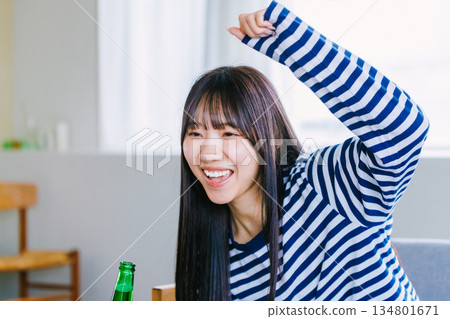 Young woman drinking beer and watching sports at home Young woman drinking beer and watching sports at home 134801671