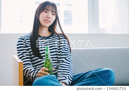 年輕女子在家中客廳喝啤酒 134801710