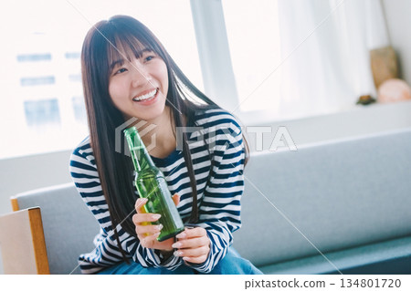 Young woman drinking beer in the living room at home 134801720