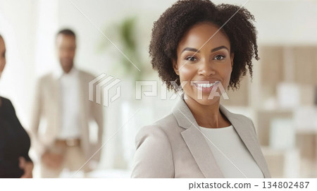 Smiling African American businesswoman in an office setting, professional team interaction Smiling African American businesswoman in an office setting, professional team interaction 134802487