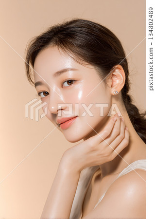 特寫鏡頭:一位微笑的年輕女子,手托著下巴,肌膚容光煥發,美麗動人。 特寫鏡頭:一位微笑的年輕女子,手托著下巴,肌膚容光煥發,美麗動人。 134802489