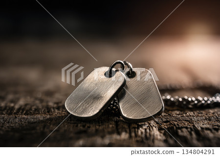 Dog tags rest on wooden background with soft light, symbolizing soldier identity and service, evoking sense of honor and remembrance Dog tags rest on wooden background with soft light, symbolizing soldier identity and service, evoking sense of honor and remembrance 134804291