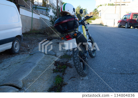 Motorcycle Parked on Urban Street With Helmet and Gear Near Curb Motorcycle Parked on Urban Street With Helmet and Gear Near Curb 134804836