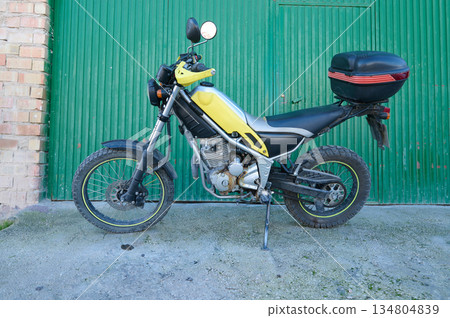 Yellow Motorcycle With Top Case Parked By Green Door On Urban Street Yellow Motorcycle With Top Case Parked By Green Door On Urban Street 134804839