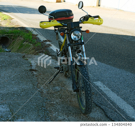 Yellow Motorcycle With Handguards Parked On Rough Road 134804840