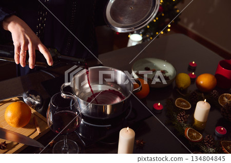 Mulled Wine Preparation Scene With Candles, Citrus, and Holiday Decorations in Winter Evening 134804845