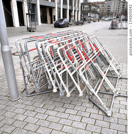 A stack of folding metal barriers with red and white stripes on the streets of the city A stack of folding metal barriers with red and white stripes on the streets of the city 134805042