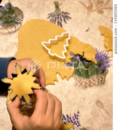 Children's hands cut out snowflake and tree-shaped cookies from raw dough. Children's hands cut out snowflake and tree-shaped cookies from raw dough. 134805060