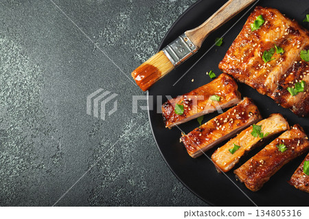 Hot grilled spare ribs from a summer BBQ served on a plate with sauce. Top view. Copy space Hot grilled spare ribs from a summer BBQ served on a plate with sauce. Top view. Copy space 134805316