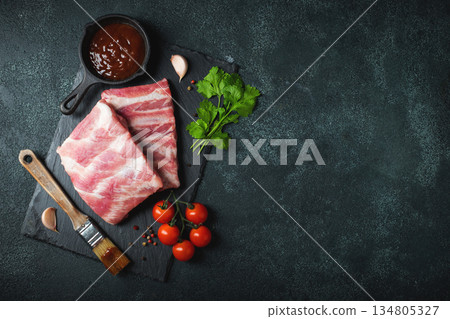 Raw meat. Raw pork ribs from the back with meat on a black background. background image 134805327