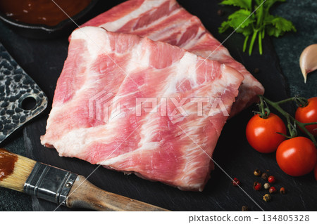Raw meat. Raw pork ribs from the back with meat on a black background. background image Raw meat. Raw pork ribs from the back with meat on a black background. background image 134805328