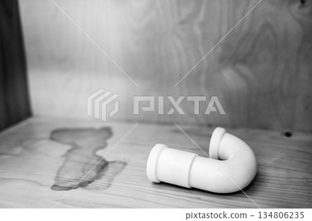 Curved plumbing pipe resting on a wooden surface in a well-lit room during the daytime Curved plumbing pipe resting on a wooden surface in a well-lit room during the daytime 134806235