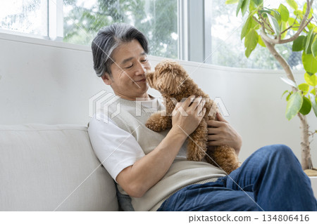 A man in his 50s holding a toy poodle - image of life with a dog 134806416