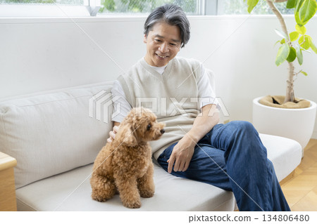 一位中年男子和他的狗在沙發上放鬆休息。這是有狗相伴生活的寫照。 134806480