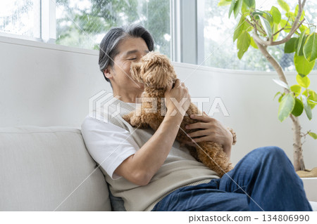 A middle-aged man holding his beloved dog. Image of life with a dog. A middle-aged man holding his beloved dog. Image of life with a dog. 134806990
