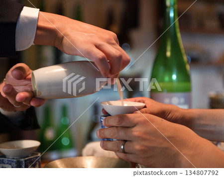 A moment before the toast, as sake is poured into a small cup A moment before the toast, as sake is poured into a small cup 134807792