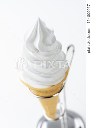 Close-up of vanilla soft serve ice cream cone and metal stand on white background Close-up of vanilla soft serve ice cream cone and metal stand on white background 134809057