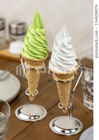 咖啡桌上擺放著兩個抹茶和香草口味的軟冰淇淋甜筒，配有金屬支架。 134809074