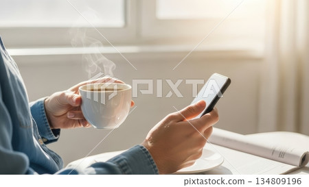 清晨咖啡時光：在明媚的陽光下享受我的智慧型手機和報紙。 134809196