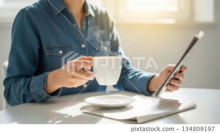 Morning coffee time: Enjoying my smartphone and newspaper in the bright sunshine 134809197