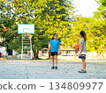 Two young girls playing basketball together on outdoor court 134809977