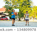 Two young girls playing basketball together on outdoor court 134809978