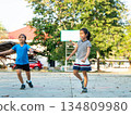 Two young girls playing basketball together on outdoor court 134809980