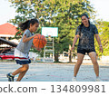Mother and daughter played basketball together on an outdoor court during sunset. 134809981
