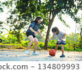 Mother and daughter played basketball together on an outdoor court during sunset. 134809993