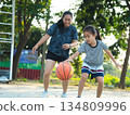 Mother and daughter played basketball together on an outdoor court during sunset. 134809996