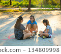 Asian mother and daughters sitting on court, resting and talking after playing basketball. 134809998