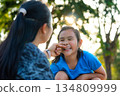 Affectionate Asian mother playing and pinching her daughter's cheek with love. 134809999
