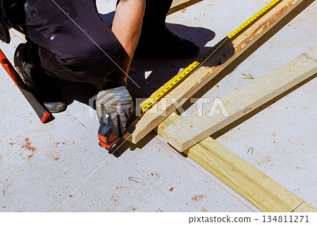 Worker is measuring wooden beams boards with tape measure on construction site Worker is measuring wooden beams boards with tape measure on construction site 134811271