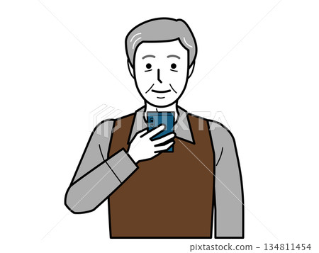 Front view. An elderly man wearing a shirt and vest looking at his smartphone. Front view. An elderly man wearing a shirt and vest looking at his smartphone. 134811454