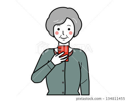 Facing forward. An elderly woman wearing a cardigan looking at her smartphone. 134811455