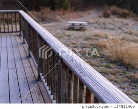 Frost-covered wooden handrail 134811469