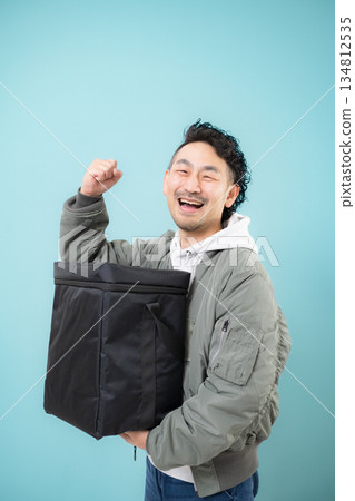 微笑的送餐員手提外帶袋，準備送餐，外帶服務工作畫面，綠色背景 134812535