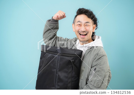 Smiling delivery person holding a delivery bag for food delivery, work image of delivery service Smiling delivery person holding a delivery bag for food delivery, work image of delivery service 134812536