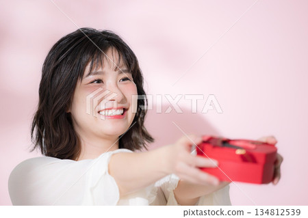 A woman smiling and holding a Valentine's Day gift. An image of a gift for confession, events, or gifts. 134812539