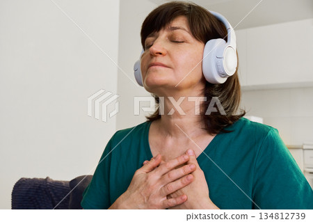 Woman wearing headphones with eyes closed embracing self-care and mindfulness at home Woman wearing headphones with eyes closed embracing self-care and mindfulness at home 134812739