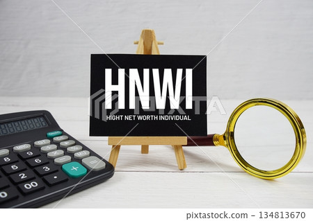 HNWI abbreviation of High Net-Worth Individual text with magnifying glass and calculator on wooden background 134813670