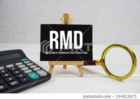 RMD abbreviation of Required Minimum Distribution text with magnifying glass and calculator on wooden background RMD abbreviation of Required Minimum Distribution text with magnifying glass and calculator on wooden background 134813673
