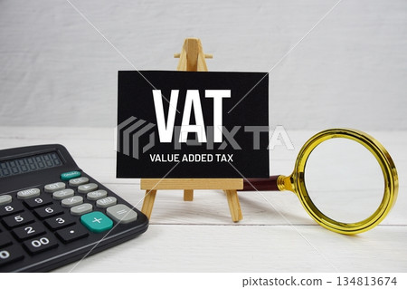 VAT abbreviation of Value Added Tax text with magnifying glass and calculator on wooden background VAT abbreviation of Value Added Tax text with magnifying glass and calculator on wooden background 134813674