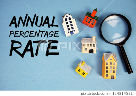 APR Annual Percentage Rate text with house models and magnifying glass on blue background 134814551